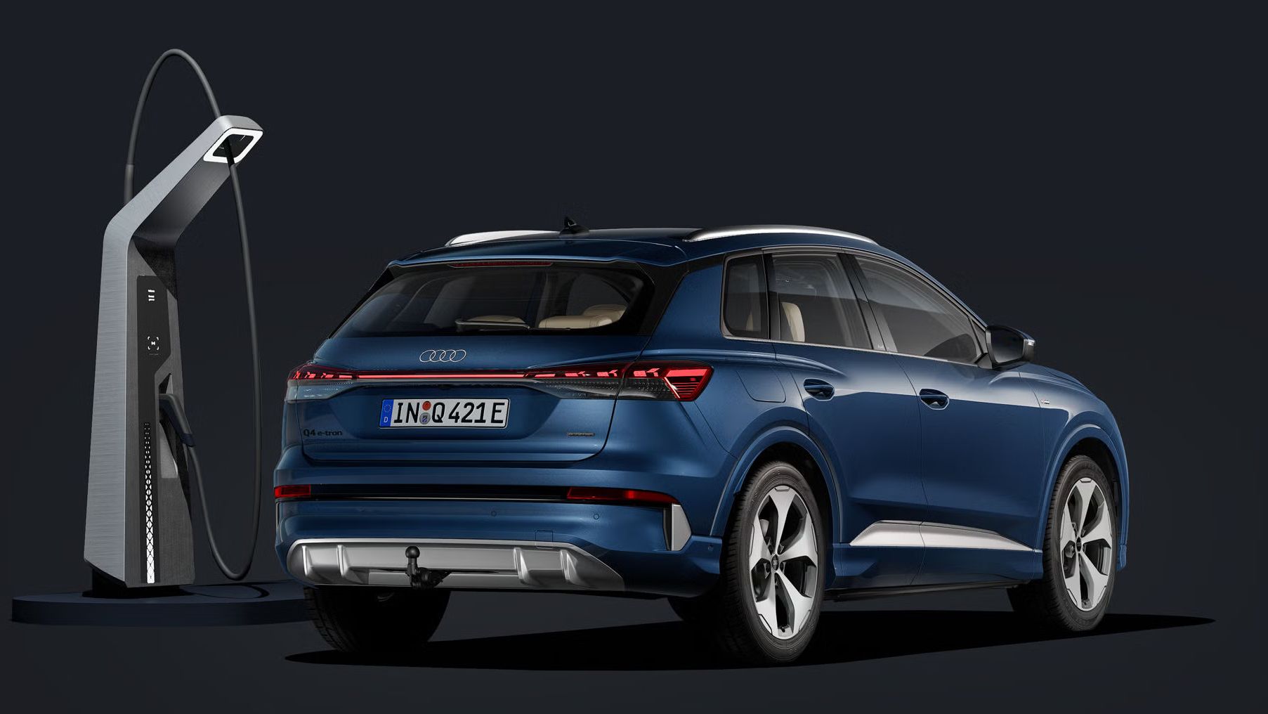 Der Q4 SUV e-tron von schräg hinten auf dunklem Hintergrund, flankiert von einer modernen Ladesäule.