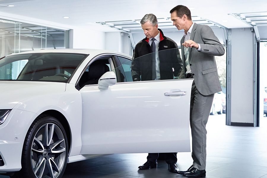 Dois senhores a olhar para o interior de um automóvel Audi