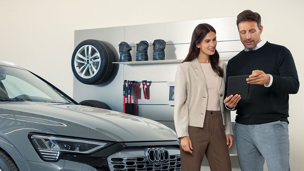 Senhor e senhora à frente de um automóvel Audi