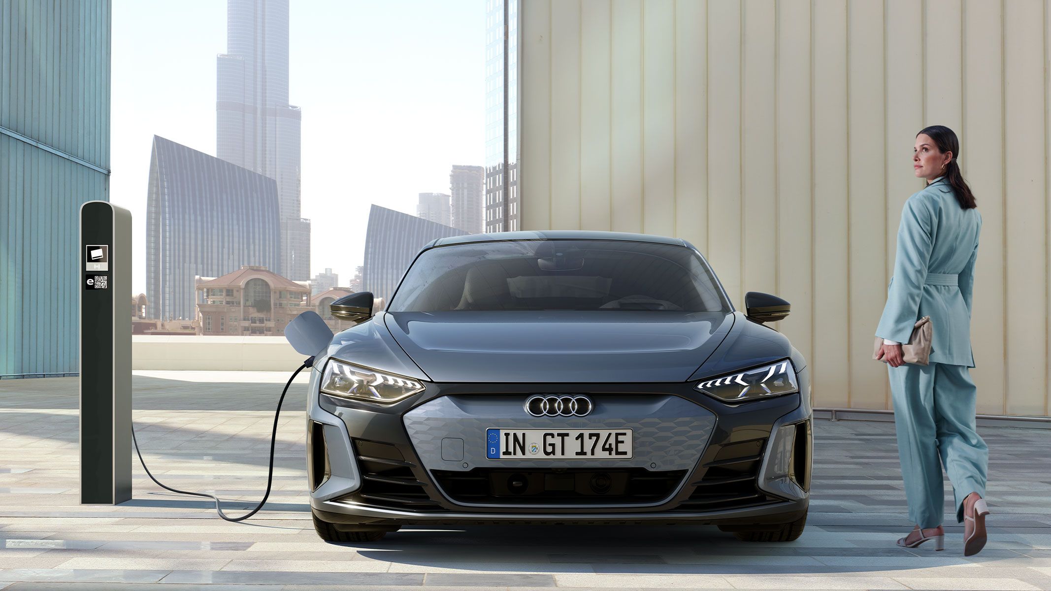 Senhora de costas ao lado de um Audi a carregar