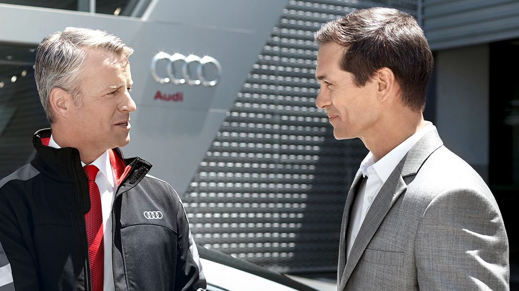Vendedor Audi a falar com um potencial cliente em frente a um automóvel Audi