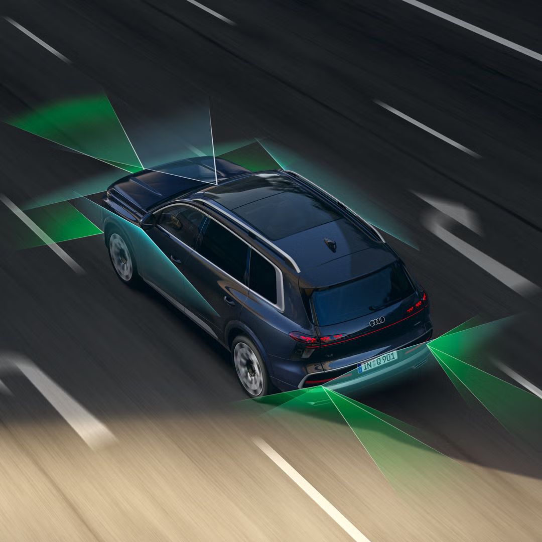 Carro em andamento numa estrada de asfalto rodeado de luzes que demonstram a visibilidade do assistente inteligente no Audi Q9