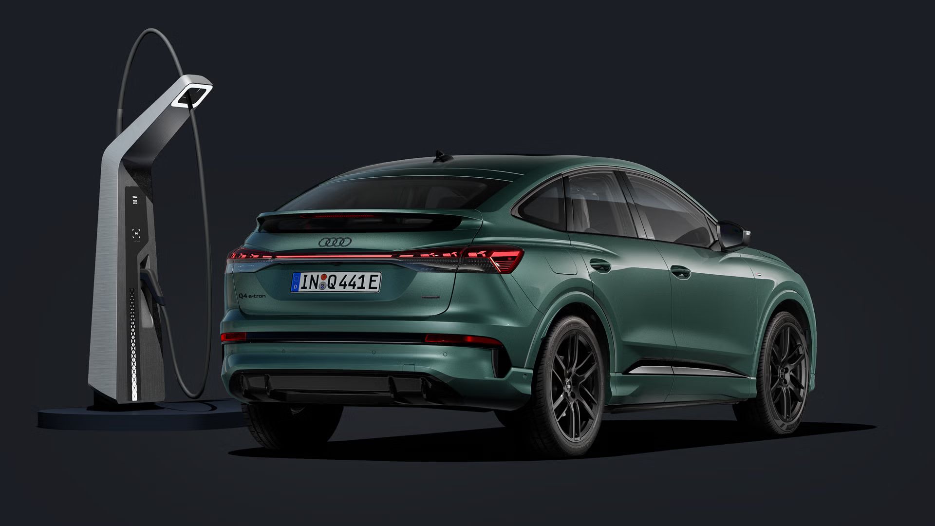 Der Q4 Sportback e-tron von schräg hinten auf dunklem Hintergrund, flankiert von einer modernen Ladesäule.