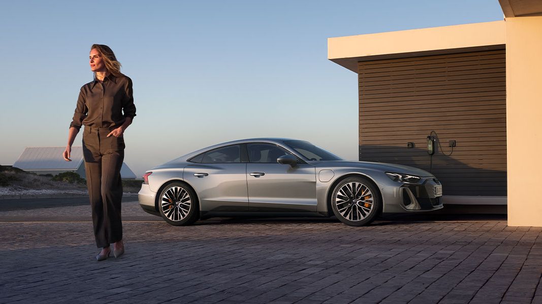 Senhora a andar com um Audi estacionado atrás dela