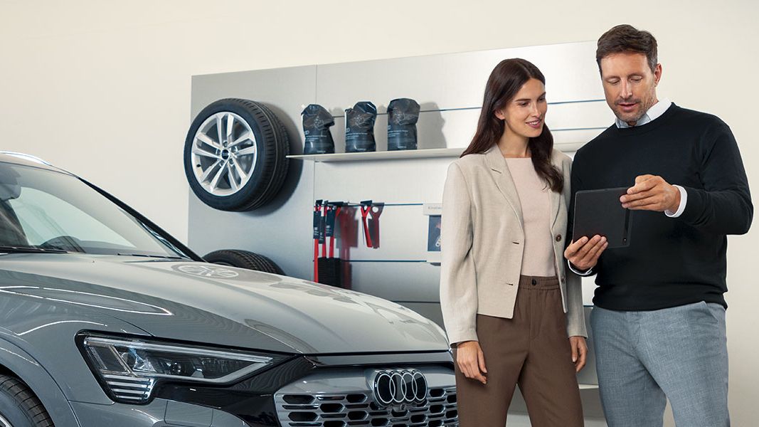 Senhor e senhora à frente de um automóvel Audi