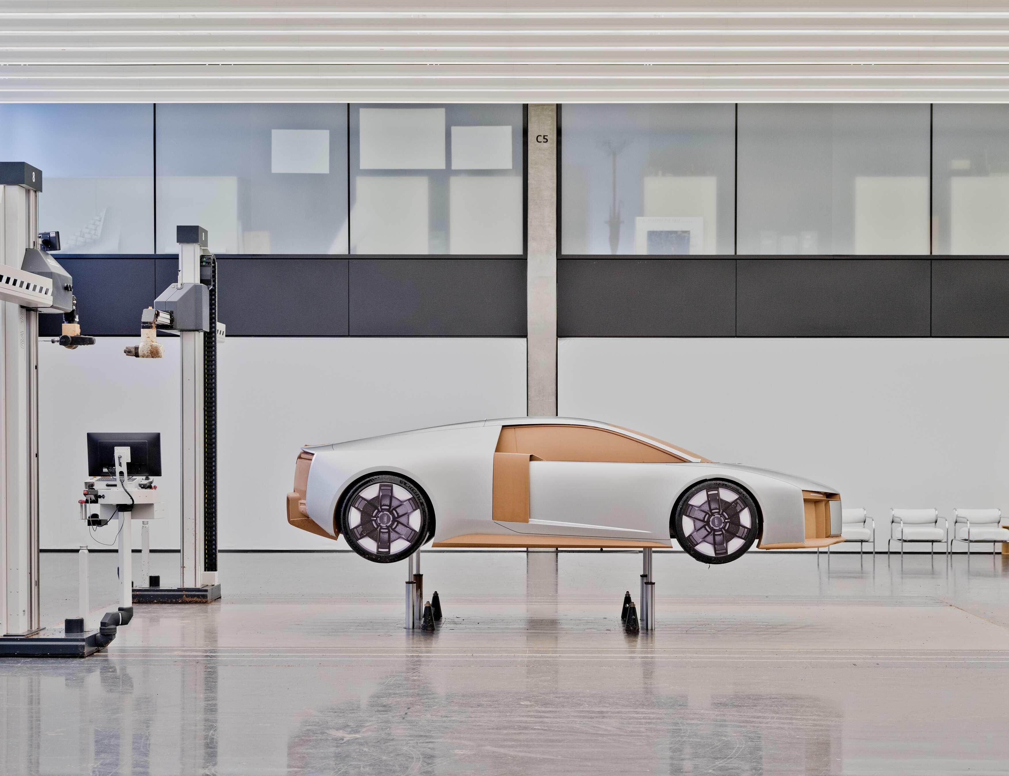 Modelo em escala de um audi Nuvolari, sem janelas nem detalhes internos, montado sobre suportes num estúdio de design limpo e minimalista. 